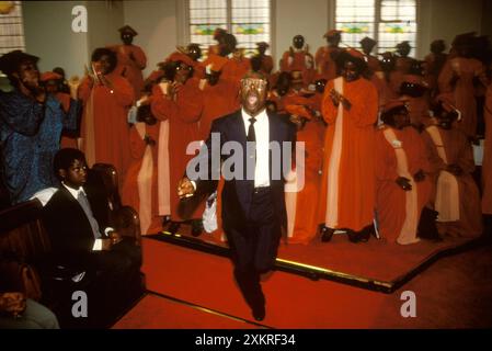 Brixton, London, England circa 1990. The Calvary Church of God in Christ, a member is filled with the Holy Spirit he dances joyously as he runs around the church interior, while the red robbed choir of the Calvary Church of God in Christ carry on singing. Stock Photo