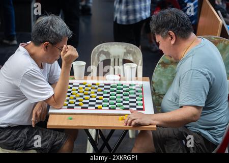 Two Chinese middle age men are playing competitive chess game against each other at Chinatown, Singapore. Stock Photo