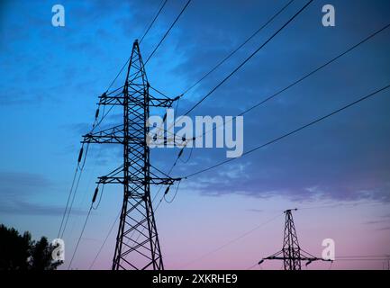 Majestic high-voltage power lines against the backdrop of a beautiful sunset. Metal wires on a high-voltage tower transmit electricity over long dista Stock Photo