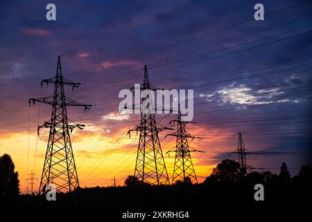 Majestic high-voltage power lines against the backdrop of a beautiful sunset. Metal wires on a high-voltage tower transmit electricity over long dista Stock Photo