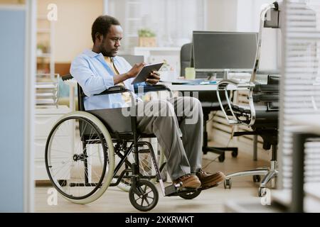 African American programmer with disability using silver touchpad in office of high-end company Stock Photo