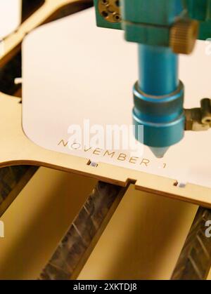 Laser cutting plywood and engraving wood inscription text November specialized machine cut tree on sawmill. close-up, vertical, inside Stock Photo