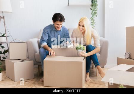 Happy man and woman putting things in moving boxes packing indoor. Preparing for renovation or leaving house. Copy space Stock Photo