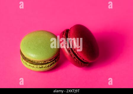 A two, red macarons with a strawberry and pistachio filling is shown in a close-up view. The macaron is isolated on a white background, which highligh Stock Photo