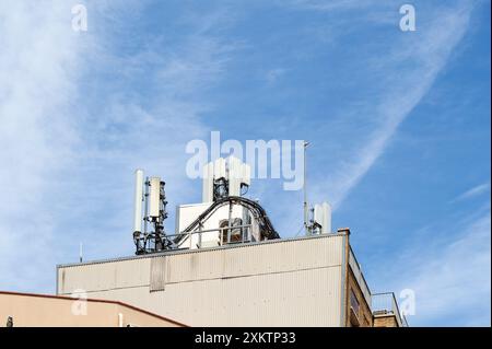 Close-up of antennas and satellite dishes atop a building against a clear blue sky highlighting urban communication technology Stock Photo