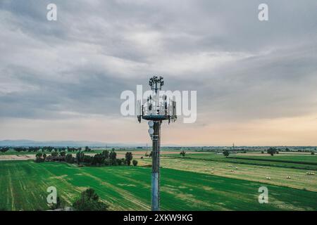 Aerial, Telecommunication tower standing in a cultivated agricultural field, ensuring communication coverage in remote rural areas. Drone view, pov Stock Photo