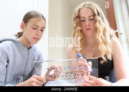 Girls doing maths math sitting on floor writing on whiteboard with pens ...