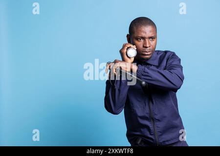 Mall security guard doing a control sweep during his night patrol duty, using a flashlight in the dark and holding his baton. Agent using a lantern to ensure safety on the perimeter. Stock Photo