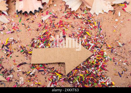 Arrow cut out of paper amid pencil shavings on canvas Stock Photo