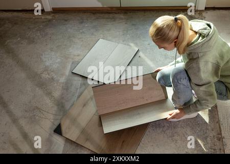 Interior Decorator Holds Luxury Vinyl Wood Samples On Concrete Floor In Condo. Selecting Waterproof Flooring. Home Reconstruction. Vinyl Tiles Stock Photo