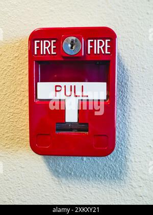 Red fire alarm box with "PULL" handle for emergencies, close-up Stock Photo