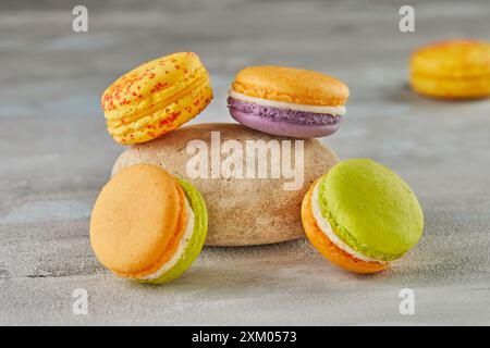 Colorful macarons with stone on concrete background. Stock Photo