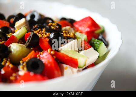 Summer salad. Classic Greek salad includes tomatoes, cucumbers, red pepper, onion, olives, oregano, and feta cheese. Fresh mixed vegetables are in a Stock Photo