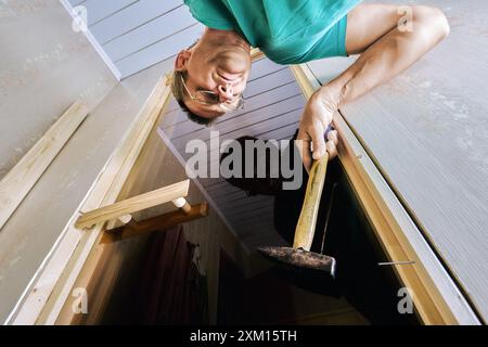 Carpenter using hammer to secure jamb to door frame, beginning with hinge side. Stock Photo