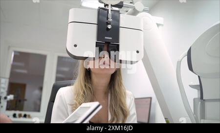 A beautiful girl is undergoing an ophthalmologic examination, checking her eye health and visual acuity. The laser beam shines into the patient's eye Stock Photo