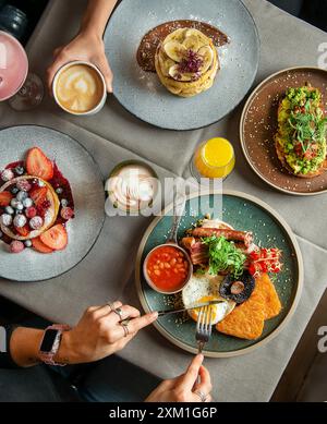 English breakfast for breakfast or lunchtime on a plate with cutlery on a woman's hands. Stock Photo