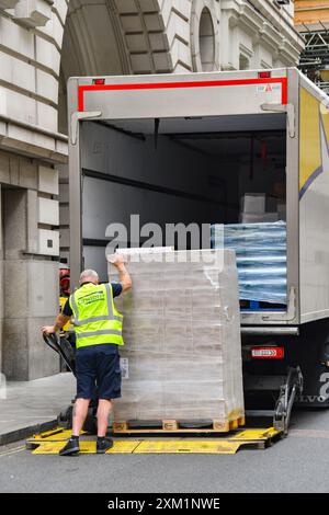 London, England, UK - 27 June 2023: Lorry driver unloading a pallet of  goods from the rear of a truck using a lift and trolley in central London. Stock Photo