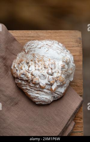 Freshly baked peanut bun with icing sugar on baking parchment, on a wooden table. Stock Photo