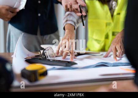 Engineers collaboration on Project Plans at Construction Site with blueprint and Tools Stock Photo