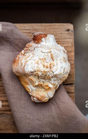 Freshly baked almond croissant with nuts on top on a wooden table. Top view Stock Photo