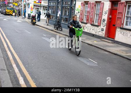Lady riding a green bicycle, Brick Lane, Spitalfields, London Stock Photo