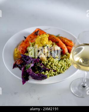 Top view of a bowl prepared with a variety of greens, vegetables and beans on a white table. Healthy food. Vegan, vegetarian food. Stock Photo