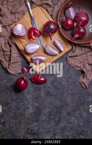 Top view of ripe red onion bulbs and chopped onion on a stone surface, flat lay with copy space for text Stock Photo
