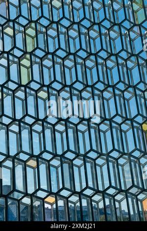 Geometric glass facade of modern building with honeycomb pattern reflecting sky Stock Photo