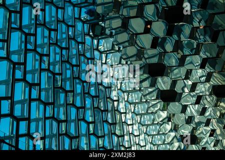Modern building facade with hexagonal glass windows reflecting sky Stock Photo