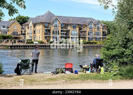 Two middle aged men fishing in the River Thames at Walton on a sunny summers day Surrey England UK Stock Photo