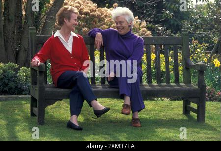two mature women chatting on bench Stock Photo