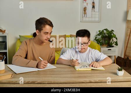 Two boys are sitting at a table, writing in notebooks. Stock Photo