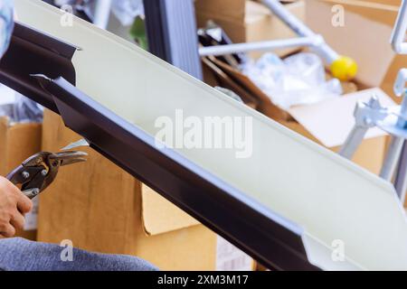 Worker cuts aluminum rain gutters to required size after they have been bent using machine tool Stock Photo