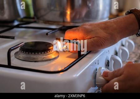 hand adjusting gas burning from a kitchen gas stove Stock Photo
