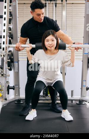 Asian Man And Woman In A Gym Doing Squats Stock Photo