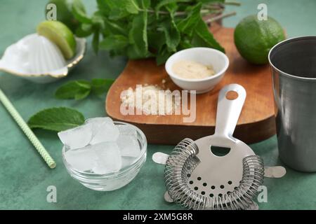 Wooden cutting board, strainer and ingredients for mojito on green background, closeup Stock Photo