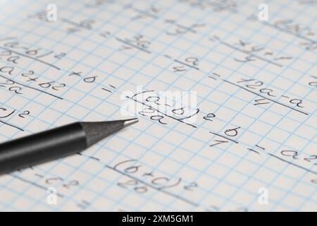 Copybook with handwritten maths formulas and pencil as background, closeup Stock Photo