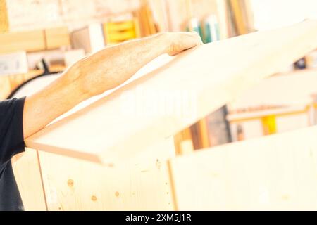 Skilled carpenter creating unique furniture in cozy workshop, highlighting natural wood grain with precision and care. Craftsmanship reflects dedicati Stock Photo