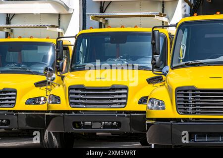 Middle duty Industrial standard yellow day cab rig semi trucks with box trailers for local deliveries and small business needs standing on the warehou Stock Photo