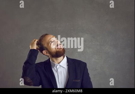 Man businessman in suit thinking scratching head in bewilderment Stock Photo