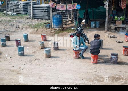 Rajasthan, India 14 February 2024 men sitting on empty oil cans outside a workshop in the street in India Stock Photo