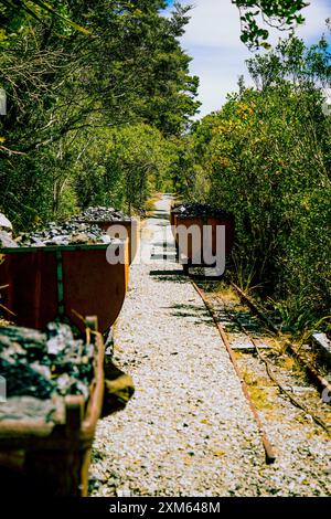 An old coal wagon rests on the rusted tracks of Denniston Mine Stock Photo