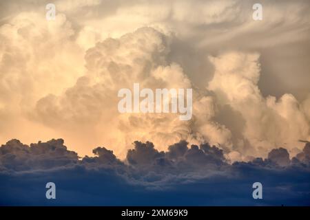 Dramatic cloudscape of a thunderstorm with cumulus nimbus clouds in warm Dawn light Stock Photo