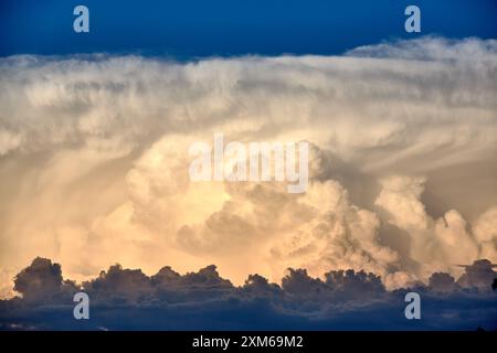 Dramatic cloudscape of a thunderstorm with cumulus nimbus clouds in warm Dawn light Stock Photo