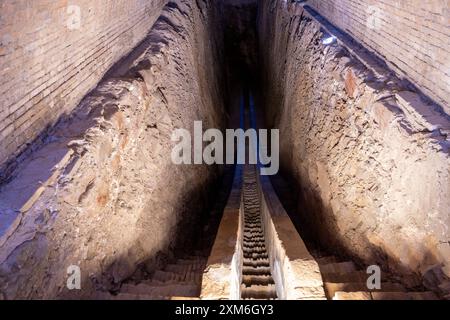 A long, narrow tunnel with a staircase leading down Stock Photo