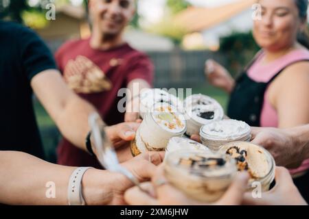 Friends cheering with jars of desserts in the backyard Stock Photo