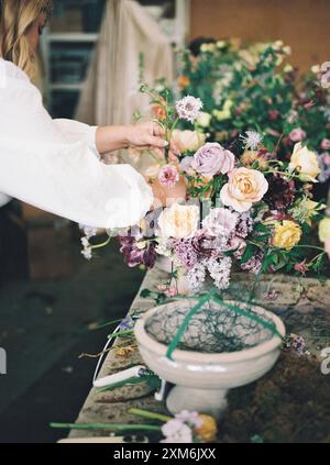 Woman arranging a bouquet of mixed flowers on a worktable Stock Photo