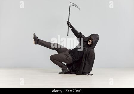 Male person in grim reaper death costume and skeleton mask having fun and dancing Stock Photo