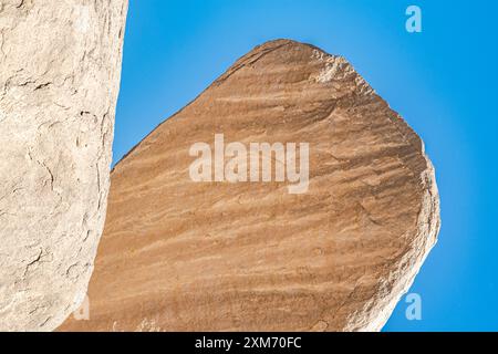 Huge sedimentary rocks naturally sculpted in the Sahara desert dry climate with sunlight and blue sky on background. Low angle view. Stock Photo