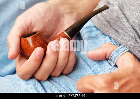 Young man holding smoking pipe in hand. Closeup view Stock Photo